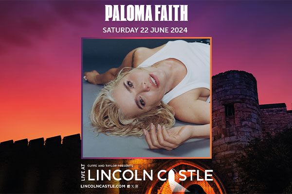 Paloma Faith laying down looking at the camera with a castle image behind her