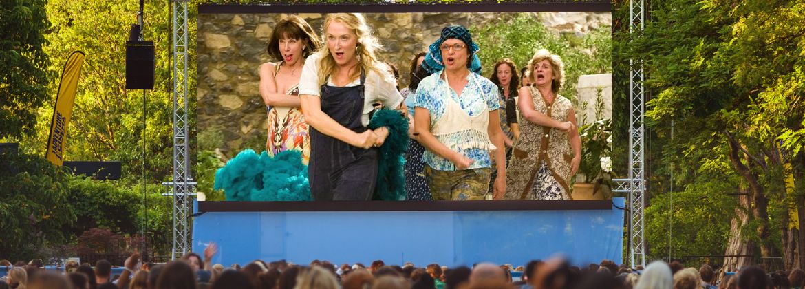 Photograph of an outdoor screen showing a scene from the film Mama Mia