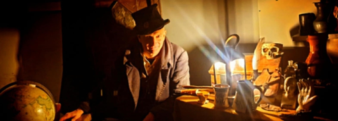 Photograph showing a story teller character dressed in Victorian style in a darkly lit room