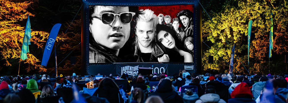 Crowd watching an outdoor cinema screening on a large screen at night