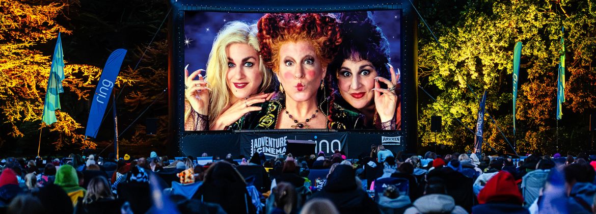 Crowd watching an outdoor cinema screening on a large screen at night