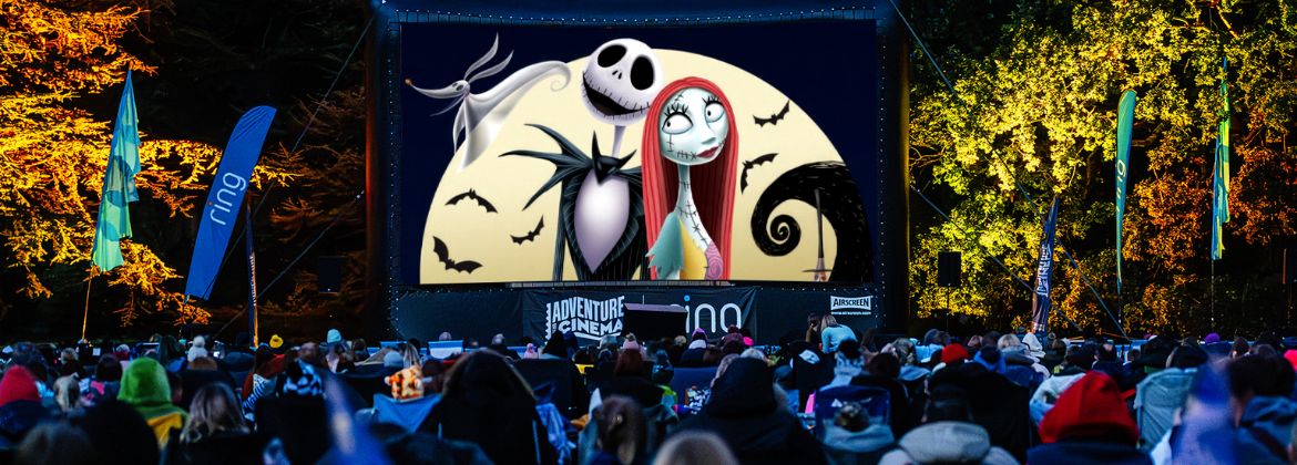 Crowd watching an outdoor cinema screening on a large screen at night