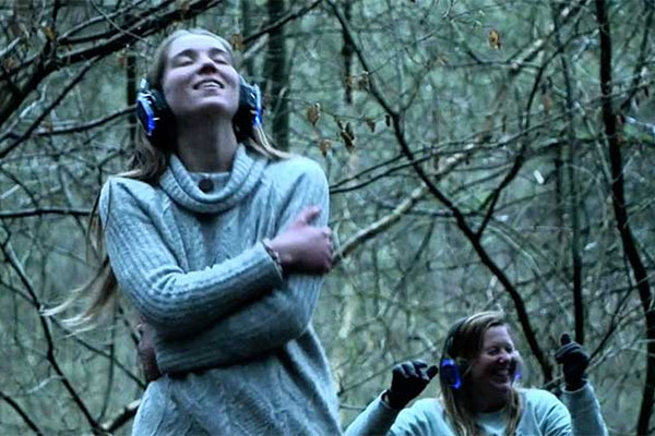 Two people dancing in the woods while listening to music on headphones